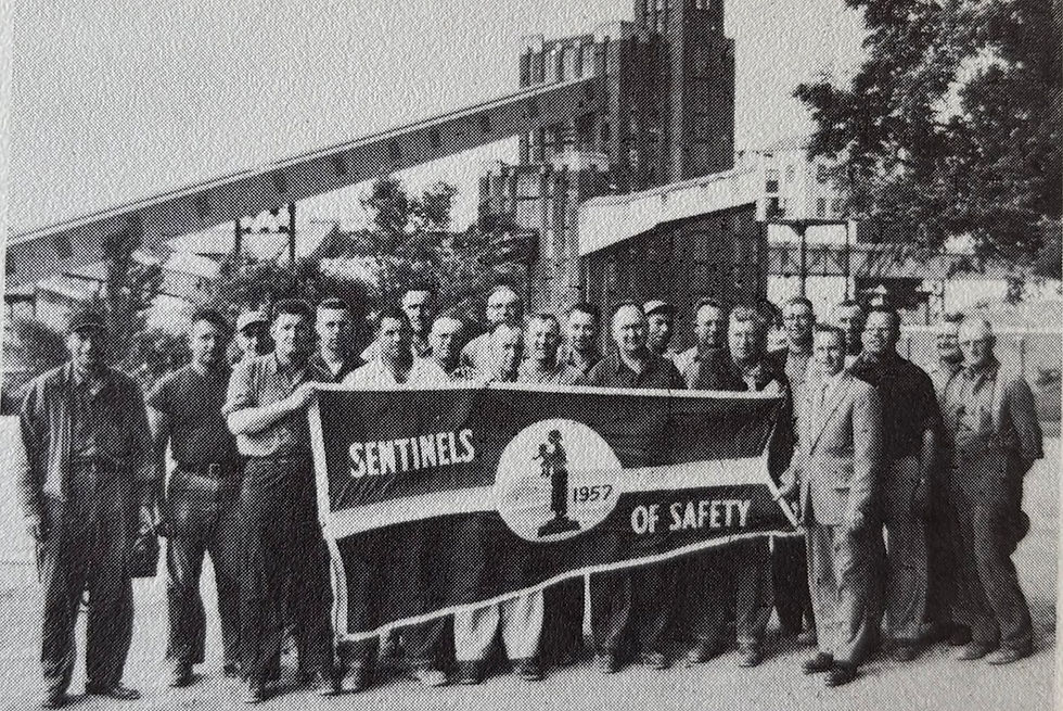 The Calcite Safety Committee proudly holds the Sentinels of Safety Flag, awarded to the plant in recognition of its outstanding safety record, 1958
