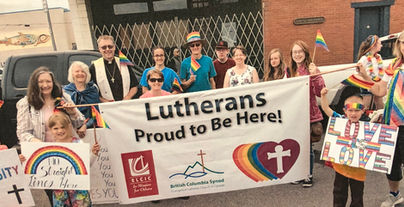 A group of people smile behind a large banner reading "Lutherans. Proud to be here!"