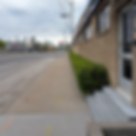 Sidewalk by brick building, street, and distant city skyline.