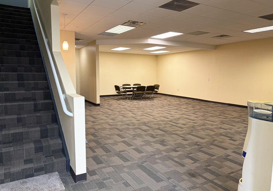 Spacious carpeted meeting room with a round table and chairs.