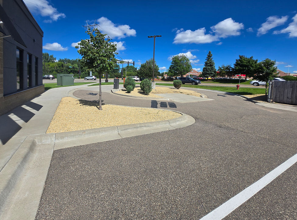 Paved drive-thru area next to a modern building under blue sky.