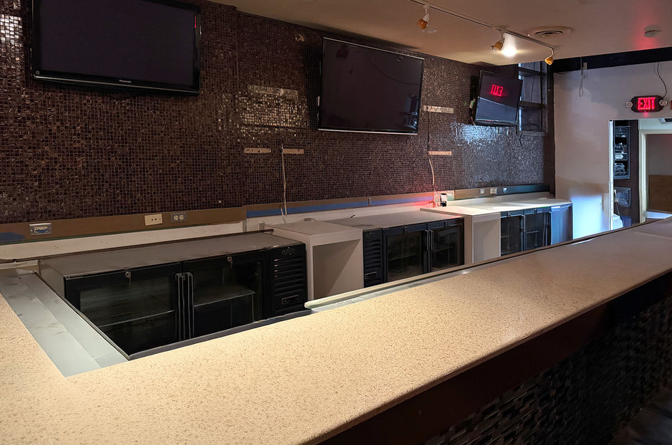 Empty bar counter, three TVs, and EXIT sign glowing red.