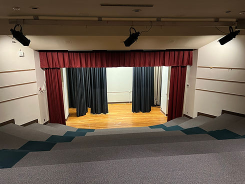 Stage with red and black curtains in a modern auditorium with stepped seating.