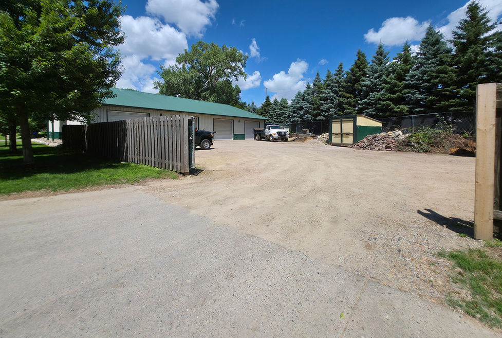 Gravel drive to industrial building. View from fence opening.