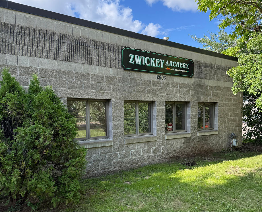 Zwickey Archery building with four windows, green grass, and trees.
