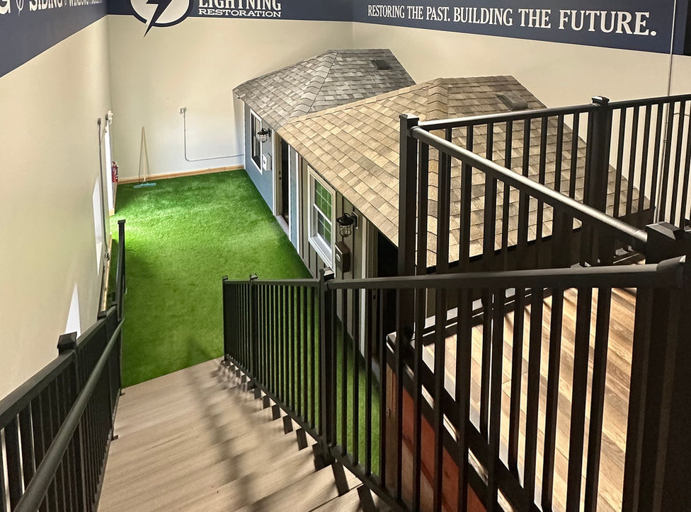 Second floor mezzanine view of stairs, green artificial turf, and offices in small model homes.