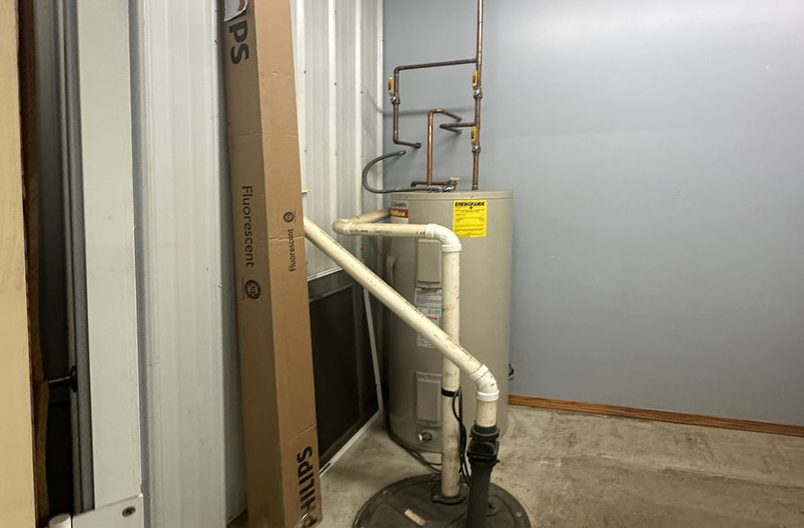 Water heater and equipment in a utility room with pipes and filter.