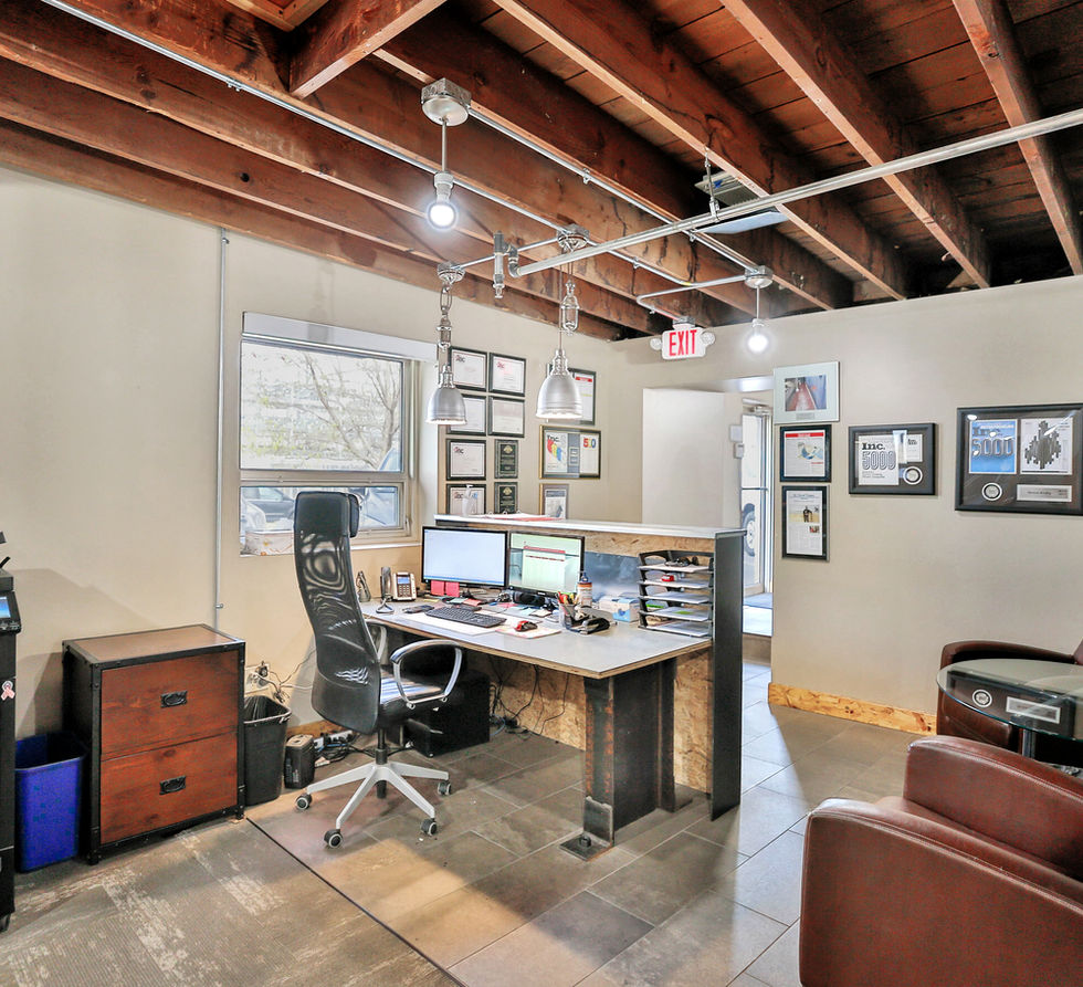 Office with desk, computers, and printer, with framed photos on the walls.