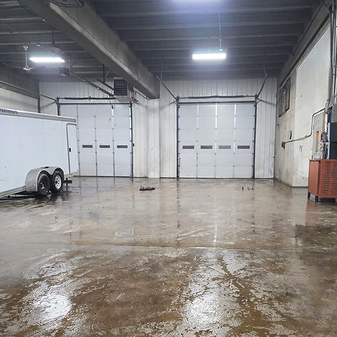 Empty industrial warehouse with wet floor and two garage doors.