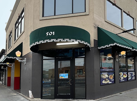 Corner building with prominent green awnings, displaying "501" address, storefront windows.