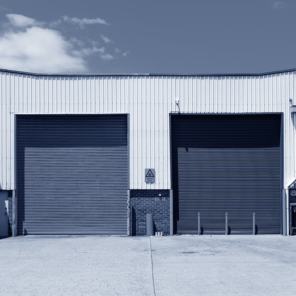 Warehouse exterior with two drive-in doors. One with barriers in front.