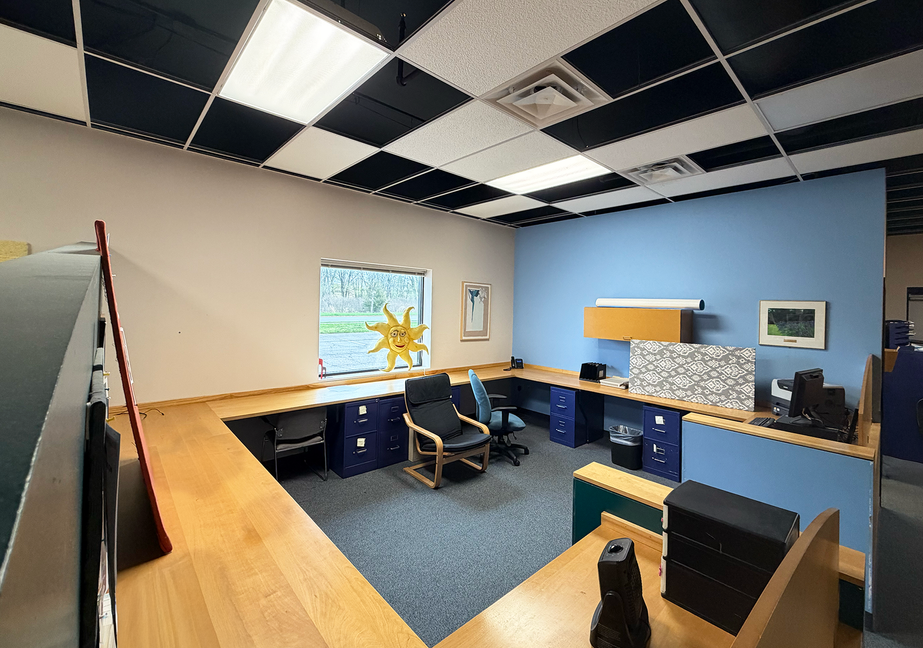 Climb Theatre office with blue walls, cubicles, and sun decor.