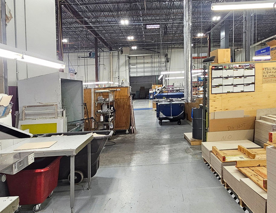 Spacious industrial warehouse interior with equipment, workbenches, and open bay door.