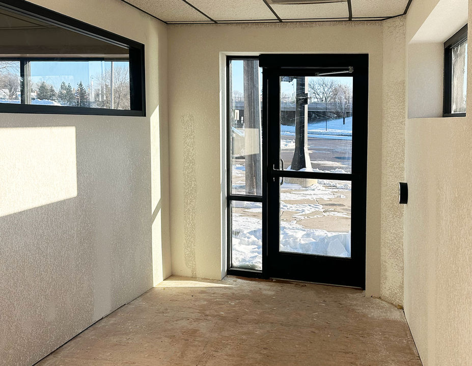 Empty commercial space with glass door and black trim, facing the outside.