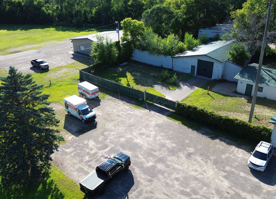Aerial view of building A including fenced area, metal building with drive-in door, and gravel parking lot.