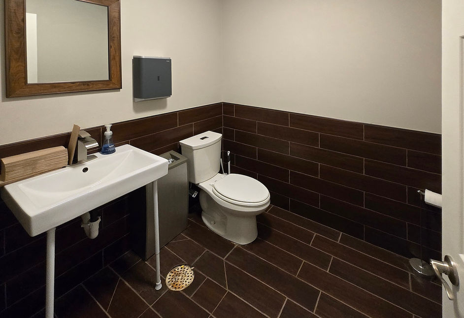 Clean restroom with updated fixtures and dark tile.