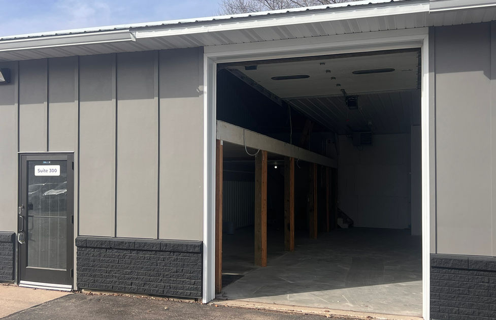 Exterior of suite 300. Board and baton, brick row on the base, pedestrian door, & open door.