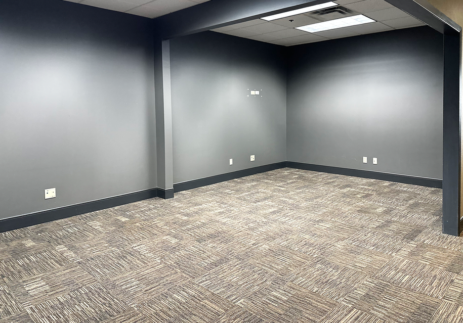 Empty office space with grey walls and patterned carpet.