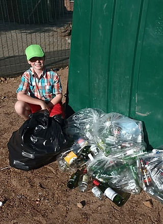 Ethan Fourie with his glass recycling collection in front of a large green drum