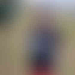 Ethan standing in front of recycling domes holding a discarded paint brush