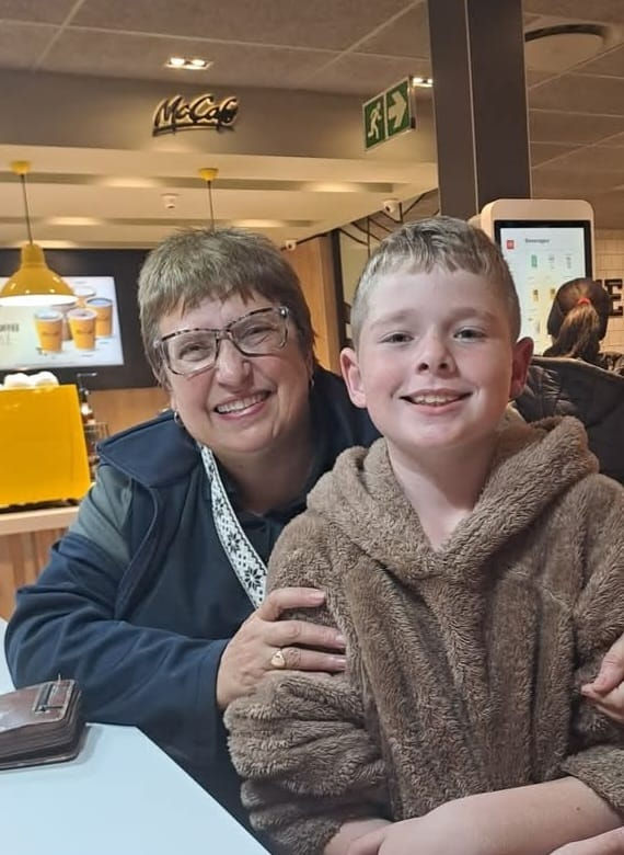 Dr Adele Botha and Ethan, The Recycling Kid at a restaurant. Warm lighting, menu in background. Casual setting, joyful mood.