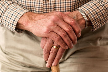 the hands of an old man holding onto his walking stick