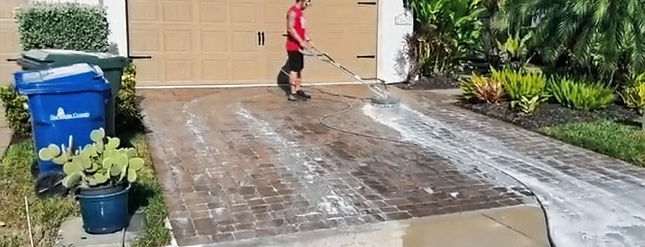 Power washing driveway pavers for sanding and sealing.