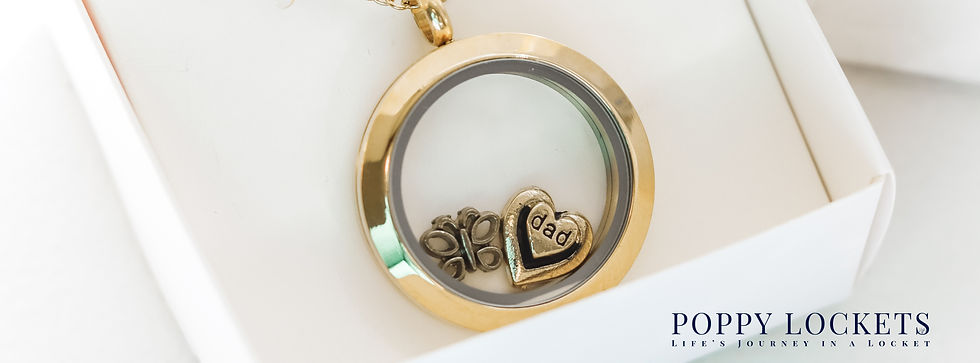 Gold locket with a heart charm inscribed "dad" and a butterflower charm, set in a white box. Text reads "Poppy Lockets: Life's Journey in a Locket."