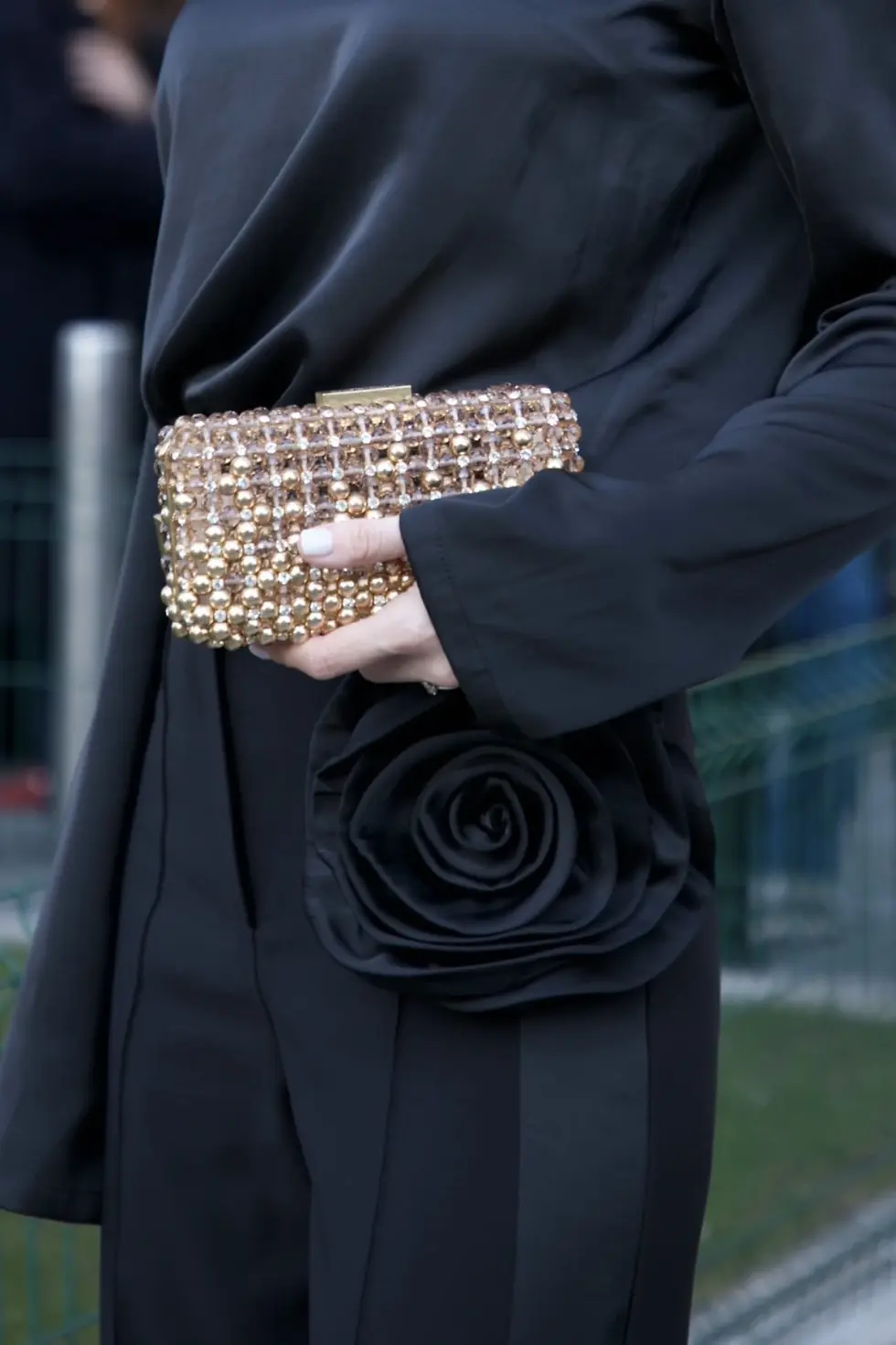 Valeriia Khrapko at Milan Fashion Week wearing REPULO'S black asymmetric silk satin blouse with scarf neck and high-waist trousers with 3D flower — Rosalie collection