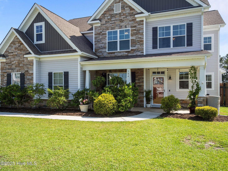 Front exterior view of a two-story home at 304 Arrington Court in Hubert, NC, featuring stone and siding facade, manicured lawn, and covered front porch.