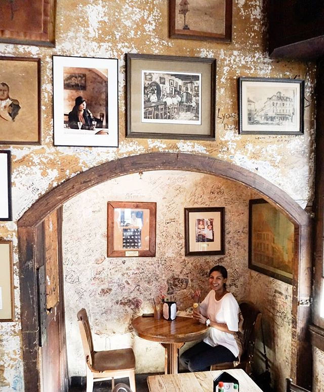 Woman sitting inside a restaurant in New Orleans. New Orleans best cocktails. 