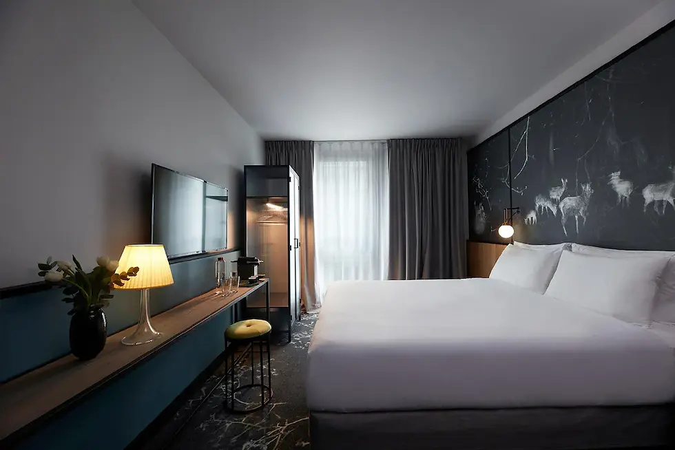 Modern hotel room with a large bed, dark accent wall featuring animal silhouettes, TV, lamp, and vase on a side table. Soft lighting, serene mood. Boutique Spa Hotel in Paris.