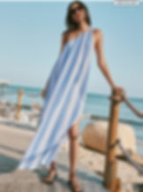 Woman in sunglasses wears a blue-and-white striped dress on a seaside boardwalk, easy to pack Las Vegas Outfits.