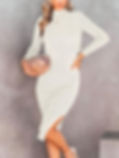 Woman in a cream ribbed turtleneck midi dress holds a blush clutch against a gray backdrop. Fun Vegas Outfits.