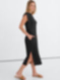 Blonde woman poses in a black sleeveless midi dress with pockets and side slit, wearing tan sandals against a white studio backdrop. Midi Dresses for Las Vegas.