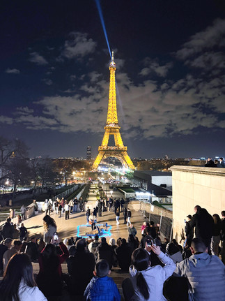 Group of people taking pictures of the Eiffel Tower from Trocadero Gardens. The Eiffel Tower lit at night.