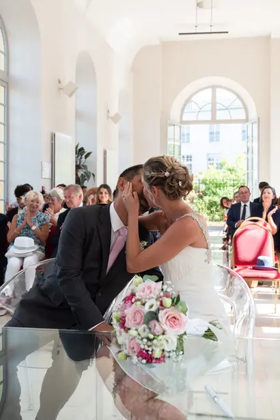 Photo d'un couple de mariés quand ils se disent "oui" à la mairie, avec un joli décor lumineux dans la réception.