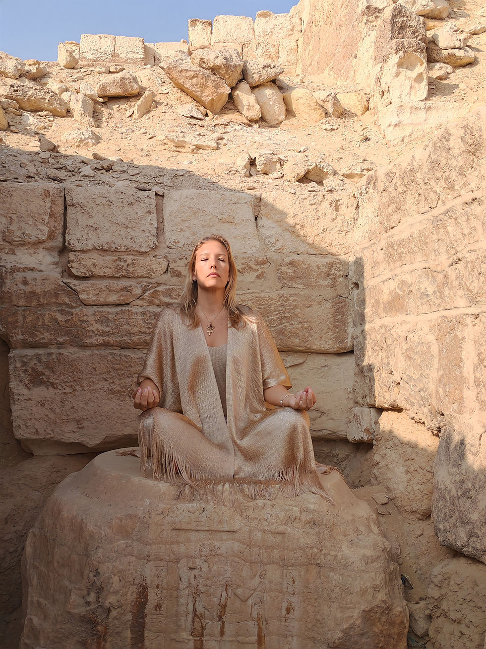 Meditating on a stone in a sandy, ancient ruin near the Pyramids of Giza. Eyes closed, wearing a gold robe, serene expression under a clear blue sky.