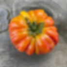 Lithium Sunset tomato showing golden-orange and coral hues with glossy skin.