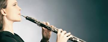 A oboe student playing the oboe in front of the teacher.