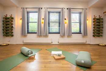 Serene yoga studio with mats, bolsters, and wooden floor
