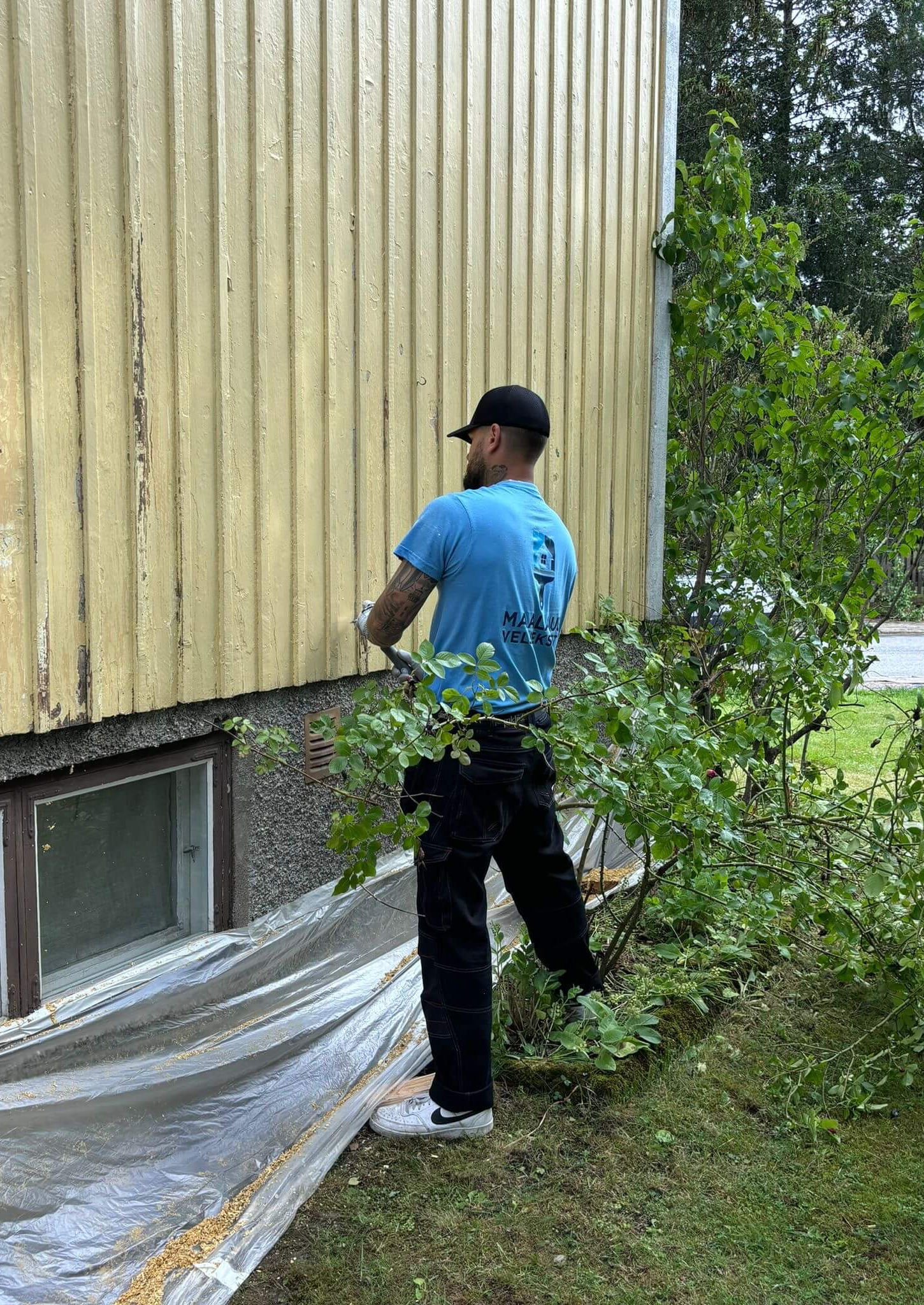 Maalari maalaa talon alaosaa Nousiaisissa ulkomaalaus