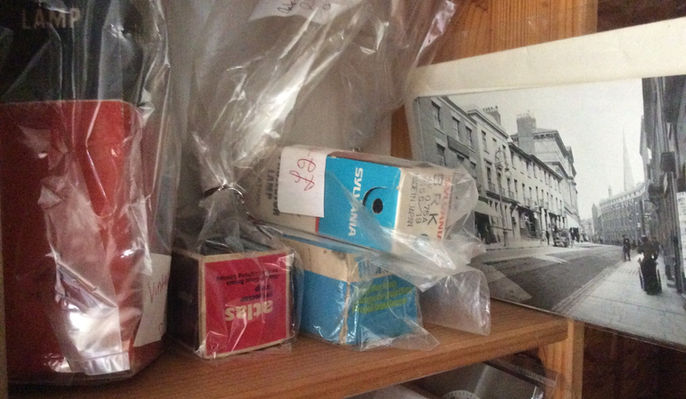 Shelf holding various objects and printed material; a black and white photo.