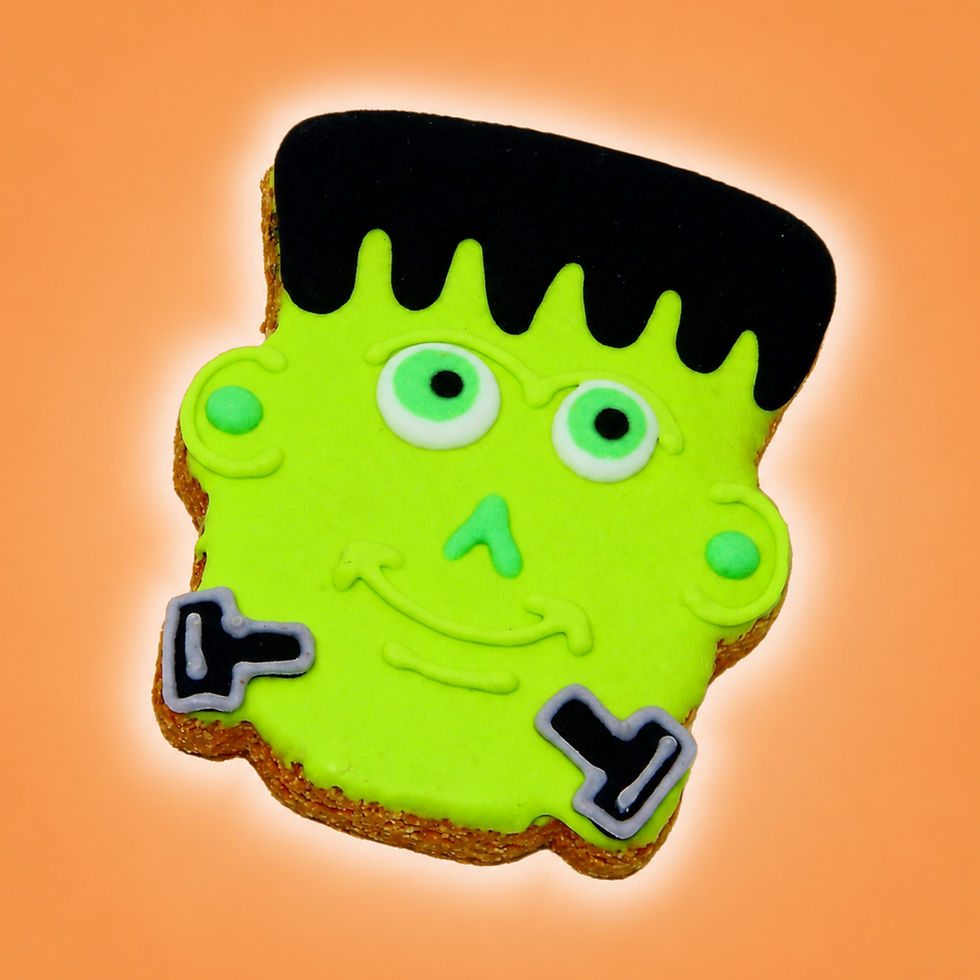 Frankenstein Halloween dog cookie with neon green icing, black hair and bolt details on orange background