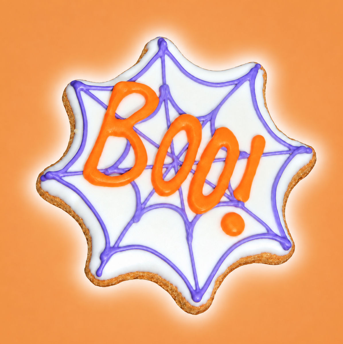 Boo spiderweb Halloween dog cookie with white icing, purple web and orange lettering on warm orange background