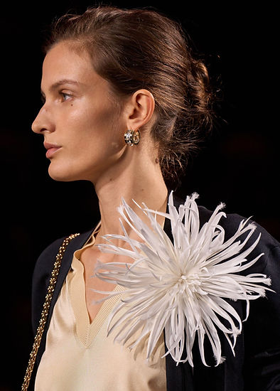 Uma modelo usando um broche de tecido com look Chanel