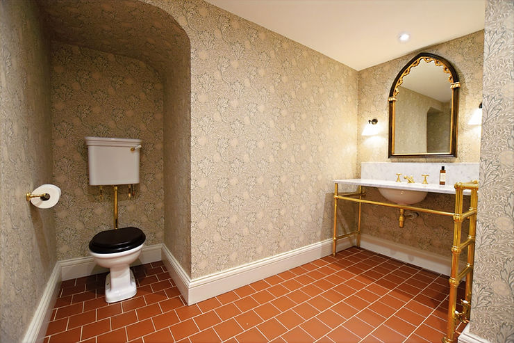Elegant bathroom featuring intricate wallpaper, a vintage-style toilet, and a stylish marble sink with gold accents.