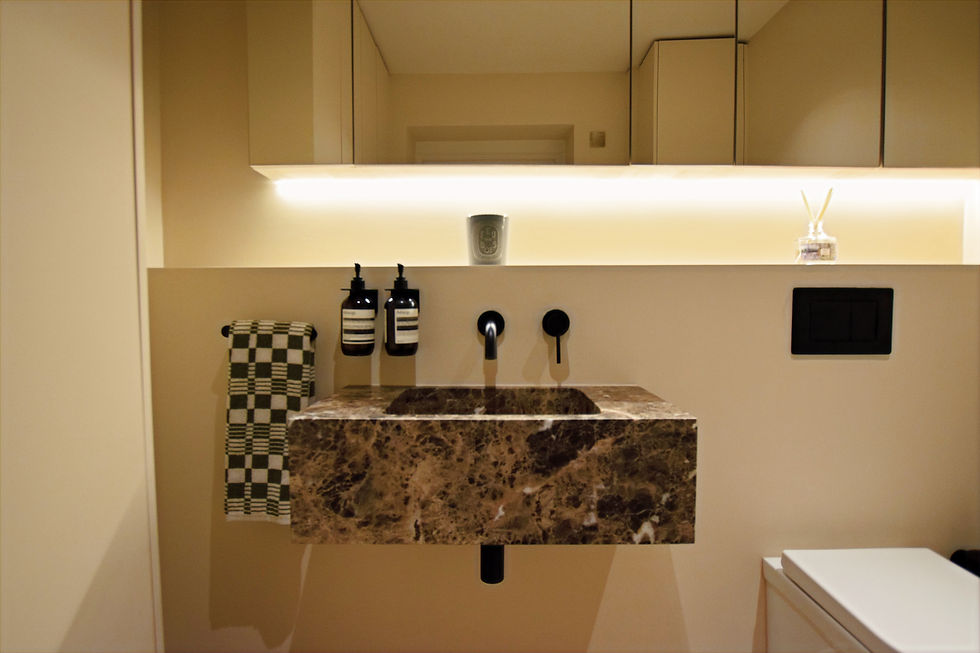 Elegant bathroom with brown marble sink, black fixtures, and a checkered towel. Beige cabinets and soft lighting create a calm ambiance.