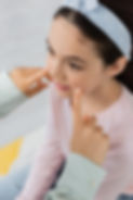 High angle view of speech therapist touching cheeks of pupil in consulting room.jpg