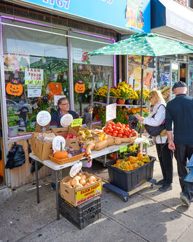 Local market with farm fresh vegetables on sidewalk.